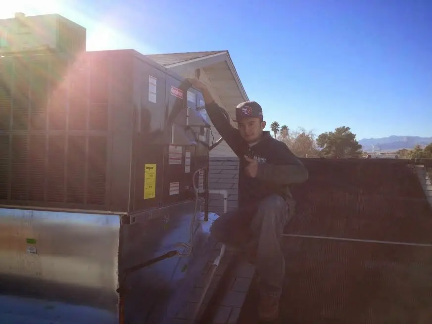 HVAC technician performing Air Duct Cleaning on a rooftop unit in Iowa City